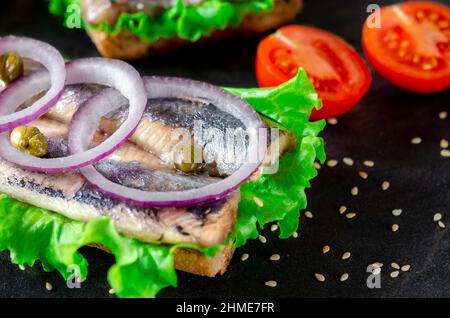 Sandwich mit Butter, Hering, roter Zwiebel und Thymian. Ein norwegischer junger Hering mit Salat Stockfoto