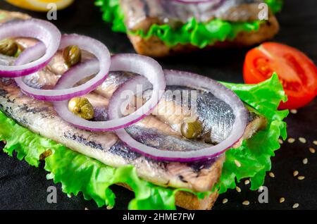 Sandwich mit Butter, Hering, roter Zwiebel und Thymian. Ein norwegischer junger Hering mit Salat Stockfoto