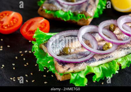 Sandwich mit Butter, Hering, roter Zwiebel und Thymian. Ein norwegischer junger Hering mit Salat Stockfoto