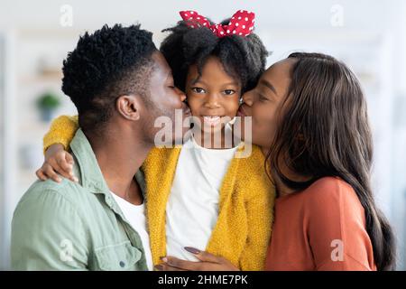 Liebevolle Familie. Glückliche Afroamerikanische Eltern Küssen Ihre Nette Kleine Tochter Stockfoto