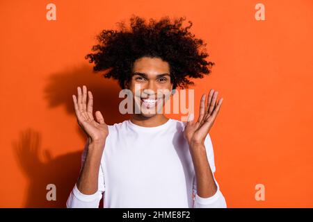 Foto von lustig aufgeregt Kerl tragen weißes Hemd aufsteigende Arme lächelnd isoliert orange Farbe Hintergrund Stockfoto
