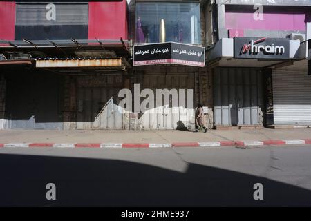 Nablus, die Stadt Nablus im Westjordanland. 9th. Februar 2022. Eine Frau geht während eines Generalstreiks an geschlossenen Geschäften vorbei, um gegen die Tötung von drei Palästinensern durch israelische Streitkräfte in der Stadt Nablus im Westjordanland am 9. Februar 2022 zu protestieren. Israel bestätigte am Dienstag, dass seine Streitkräfte drei Palästinenser im von Israel besetzten Westjordanland während einer angeblichen "Operation zur Vereitel einer Terrorzelle" getötet haben. Quelle: Nidal Eshtayeh/Xinhua/Alamy Live News Stockfoto