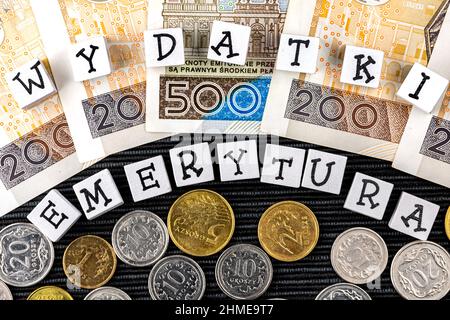 Die Formulierung "wydatki emerytury" wurde übersetzt mit "Spesenrenten" und vielen polnischen Münzen und Banknoten auf schwarzem Hintergrund. Neue Steuervorschriften in P Stockfoto