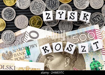 Die Formulierung "zysk koszt" wurde mit "Gewinnkosten" übersetzt und viele polnische Münzen und Banknoten auf schwarzem Hintergrund. Neue Steuervorschriften in Polen. Gewinn Stockfoto