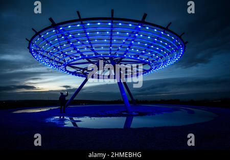 Haslingden, Lancashire, Großbritannien, Mittwoch, 09. Februar 2022. Ein Spaziergänger hält an, um das blau beleuchtete Halo Panopticon über der Stadt Haslingden, Lancashire, zu bewundern, nach einem schönen sonnigen Nachmittag. Quelle: Paul Heyes/Alamy News Live Stockfoto