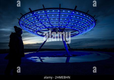 Haslingden, Lancashire, Großbritannien, Mittwoch, 09. Februar 2022. Ein Spaziergänger hält an, um das blau beleuchtete Halo Panopticon über der Stadt Haslingden, Lancashire, zu bewundern, nach einem schönen sonnigen Nachmittag. Quelle: Paul Heyes/Alamy News Live Stockfoto