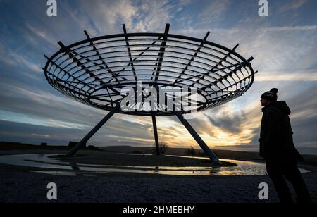 Haslingden, Lancashire, Großbritannien, Mittwoch, 09. Februar 2022. Ein Spaziergänger hält an, um die untergehende Sonne am Halo panopticon über der Stadt Haslingden, Lancashire, nach einem schönen sonnigen Nachmittag zu bewundern. Quelle: Paul Heyes/Alamy News Live Stockfoto