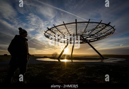 Haslingden, Lancashire, Großbritannien, Mittwoch, 09. Februar 2022. Ein Spaziergänger hält an, um die untergehende Sonne am Halo panopticon über der Stadt Haslingden, Lancashire, nach einem schönen sonnigen Nachmittag zu bewundern. Quelle: Paul Heyes/Alamy News Live Stockfoto