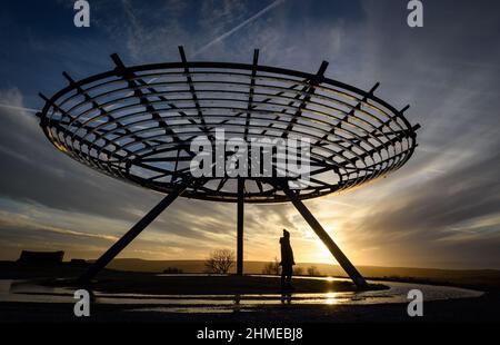 Haslingden, Lancashire, Großbritannien, Mittwoch, 09. Februar 2022. Ein Spaziergänger hält an, um die untergehende Sonne am Halo panopticon über der Stadt Haslingden, Lancashire, nach einem schönen sonnigen Nachmittag zu bewundern. Quelle: Paul Heyes/Alamy News Live Stockfoto