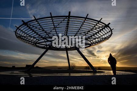 Haslingden, Lancashire, Großbritannien, Mittwoch, 09. Februar 2022. Ein Spaziergänger hält an, um die untergehende Sonne am Halo panopticon über der Stadt Haslingden, Lancashire, nach einem schönen sonnigen Nachmittag zu bewundern. Quelle: Paul Heyes/Alamy News Live Stockfoto