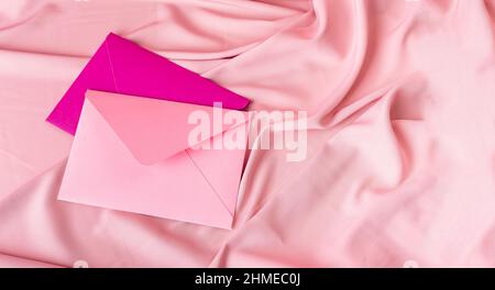 Pinke und violette Umschläge auf zartem Seidenstoff-Hintergrund mit Kopierfläche. Stockfoto