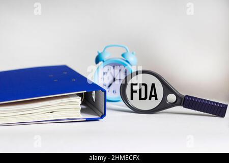 FDA-Konzept. Konzept der Food and Drug Administration. Lupe, Ordner und Uhr Stockfoto