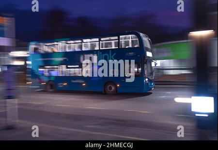 Ein unlink blauer Doppeldeckerbus, der bei Nacht fährt, wurde mit Schwenktechnik in Southampton UK mit Passagieren an Bord mit Kopierfläche aufgenommen. Stockfoto