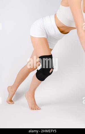 Kniestützenstrebe am Bein isoliert auf weißem Hintergrund. Elastische orthopädische Orthese. Anatomische Hosenträger für Kniefixierung, Verletzungen und Schmerzen. Schutz Stockfoto