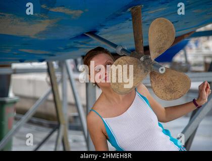 Reife Frau posiert im Trockendock neben dem Propeller einer Yacht in Spanien Teneriffa Stockfoto