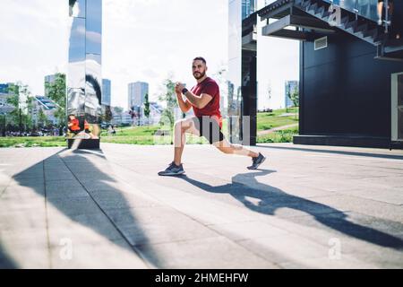 Ernsthafter Sportler, der Stretching-Übungen auf der Stadtstraße macht Stockfoto