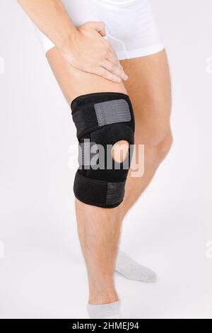 Kniestützenstrebe am Bein isoliert auf weißem Hintergrund. Elastische orthopädische Orthese. Anatomische Hosenträger für Kniefixierung, Verletzungen und Schmerzen. Schutz Stockfoto