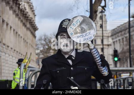 London, England, Großbritannien. 9th. Februar 2022. Ein Protestler, der als Charlie Chaplin in einer Polizeiuniform gekleidet ist, hält ein Vergrößerungsglas-förmiges Schild mit der Aufschrift „I Spy A Police Cover Up“ vor der Downing Street. Demonstranten versammelten sich in Westminster, London, als der Druck auf den britischen Premierminister Boris Johnson wegen der Lockdown-Parteien, die weithin als „Partygate“ bezeichnet werden, weiter ansteigt (Bild: © Vuk Valcic/ZUMA Press Wire) Quelle: ZUMA Press, Inc./Alamy Live News Stockfoto