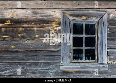 Rustikales Holzhaus aus runden Stämmen. Holzfensterrahmen schneebedecktes Dorf Stockfoto