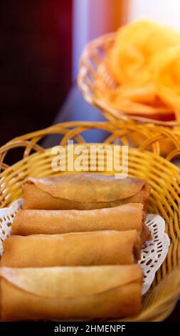 Frühlingsrollen sind eine große Auswahl an gefüllten, gerollten Vorspeisen, die in der Ost- und südostasiatischen Küche zu finden sind. Gebratene Brötchen Dim Sum auf Korb i serviert Stockfoto