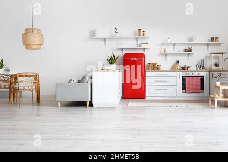 Innenausstattung der hellen Küche mit weißen Ablagen und rotem Kühlschrank Stockfoto