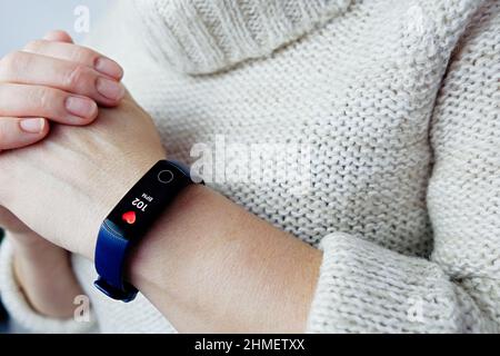 Nahaufnahme des Fitness-Trackers für hohe Herzfrequenz einer Frau. Tachykardie nach Coronavirus. Selektiver Fokus. Stockfoto