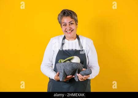 Portrait einer hispanischen Frau mittleren Alters, die in Mexiko, Lateinamerika, mexikanischer Mörser mit Saucenzutaten zubereitet und hält Stockfoto