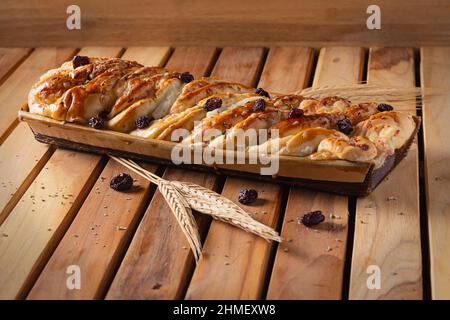 Bricohe Brot mit Rosinen und Weizenzweigen. Stockfoto