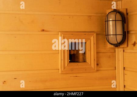 Lüftungsfenster für die Belüftung in der Sauna und eine Lampe. Stockfoto