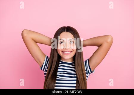 Foto von süßen glänzenden Mädchen gekleidet gestreiften Kleidung Arme hinter dem Kopf suchen leeren Raum isoliert rosa Farbe Hintergrund Stockfoto