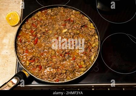 Fleisch mit Gemüse wird auf dem Herd in einer Bratpfanne, Hausmannskost, leckere und nahrhafte Speisen geschmort. Stockfoto