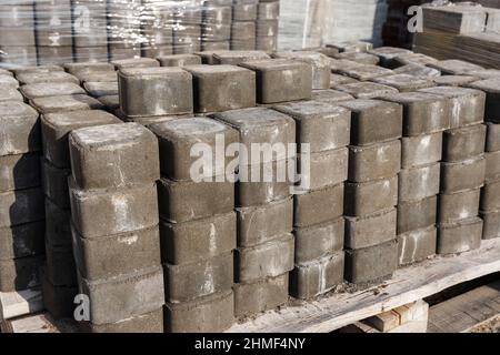 Reihen von Pflasterplatten auf einer Palette werden Pflastersteine für die Pflasterung von Straßen vorbereitet. Bau eines Fußgängerweges. Stockfoto