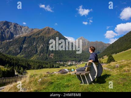 Stubaier Alpen, Wanderer auf einer Bank in der Nähe des Bergsteigerdorfes Sankt Sigmund im Sellrain, Tirol, Österreich Stockfoto