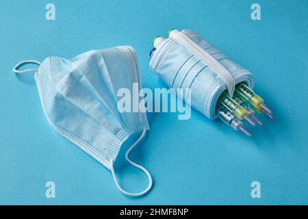 Insulin-Spritzenstifte mit medizinischen Masken auf blauem Hintergrund Stockfoto