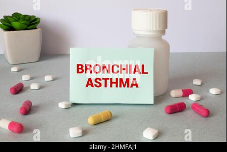 Im Notizbuch ist der Text Asthma bronchiale, neben einem Stethoskop, Pillen und Brille. Stockfoto