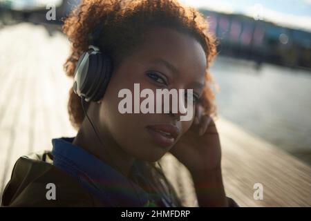 Porträt einer jungen schwarzen Frau mit großen afro Haaren, die Kopfhörer trägt Stockfoto