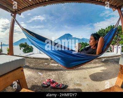 Genießen Sie eine Tasse Kaffee mit Blick auf den Vulkan San Pedro und den Atitlan-See aus einer Hängematte, San Marcos, Guatemala Stockfoto