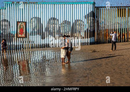 Tijuana, Mexiko. 24th Oktober 2020. Ein Paar umarmt sich am Strand von Tijuana neben der Mauer, die Mexiko von den Vereinigten Staaten trennt. (Foto von Antonio Cascio/SOPA Images/Sipa USA) Quelle: SIPA USA/Alamy Live News Stockfoto