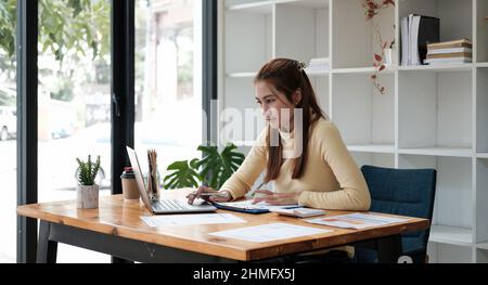 Fröhliche asiatische Frau, die im Büro arbeitet, verwenden Computer mit Kopierraum. Unternehmer Menschen kmu Freelance Online Marketing E-Commerce Telemarketing Stockfoto