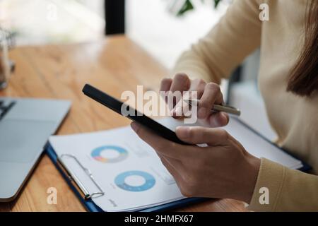 Nahaufnahme einer Frau, die das Smartphone in der Hand hält, Haushaltskosten oder Rechnungen berechnet, medizinische oder finanzielle Investitionen über mobile E verwaltet Stockfoto