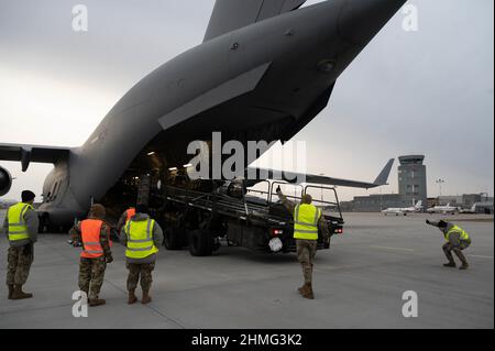 Mitglieder, die dem 435th Air Ground Operations Wing und dem 521st Air Mobility Operations Wing zugewiesen wurden, marschierung einen Lader mit 60k Flugzeugen aus einem C-17 Globemaster III, der dem 62nd Airlift Wing von der Joint Base Lewis-McChord, Washington, im Rzeszów-Jasionka Airport, Polen, zugewiesen wurde, 8. Februar, 2022. Mitglieder der 521st AMOW und der 435th AGOW sind nach Polen entsandt, um den Flughafen auf die Ankunft der US-Armee vorzubereiten. (USA Luftwaffe Foto von Senior Airman Taylor Slater) Stockfoto