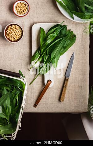 Frisch gepflückter Bärlauch, Ramson in einem weißen Metallkorb auf dem Tisch mit Leinentischtuch. Frühlingskräuter. Vegane Küche. Sauberes Essen. Saisonal Stockfoto