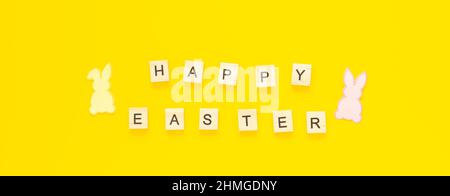 Grußkarte mit Text HAPPY EASTER und Papierkaninchen auf gelbem Hintergrund Stockfoto