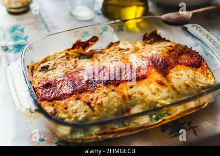 Cannelloni mit Spinat aus nächster Nähe, Tomatensauce, Bachamel und Käse auf Tischtuch. Traditionelle hausgemachte klassische italienische Küche Konzept. Stockfoto