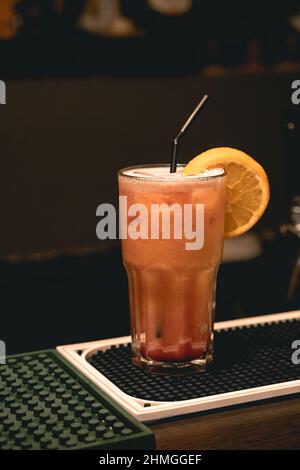 Erfrischender Eiscocktail, Tequila, Sonnenaufgang in einem hohen Glas mit Orangenscheibe und Stroh auf der Theke Stockfoto