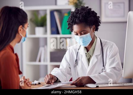 Weibliche Ärztin Im Weißen Mantel Trägt Gesichtsmaske Mit Treffen Mit Reifen Frau Patient Im Büro Stockfoto
