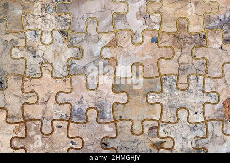 Alte, verblasste und rissige Wand-Puzzle-Collage mit goldenen Rahmen. Beton, Zement und goldene Wandmuster. Symmetrischer und abstrakter strukturierter Hintergrund. Stockfoto