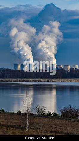 10. Februar 2022, Brandenburg, Cottbus: Blick über den Rand des ehemaligen Tagebaubetriebs Cottbus-Nord zum Braunkohlekraftwerk Jänschwalde, wo aus den Kühltürmen Dampf aufsteigt. Hier soll in wenigen Jahren der zukünftige Cottbus East Lake entstehen. Mitte April 2019 begann die Überschwemmung der ehemaligen Tagebaumine Cottbus-Nord. Das Energieunternehmen Lausitz Energie Bergbau AG (LEAG) lässt Wasser aus der Spree über den Hammergraben zum Hochwasser in den Tagebau fließen - insgesamt rund 45 Millionen Kubikmeter pro Jahr. Der riesige künstliche See soll eine haben Stockfoto