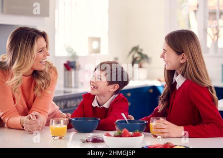 Mutter Mit Frühstück Mit Kindern In Der Schuluniform An Der Küchentisch Stockfoto