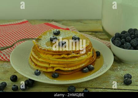Pfannkuchen mit Heidelbeeren, Ahornsirup auf einem rustikalen weißen Hintergrund. Stockfoto